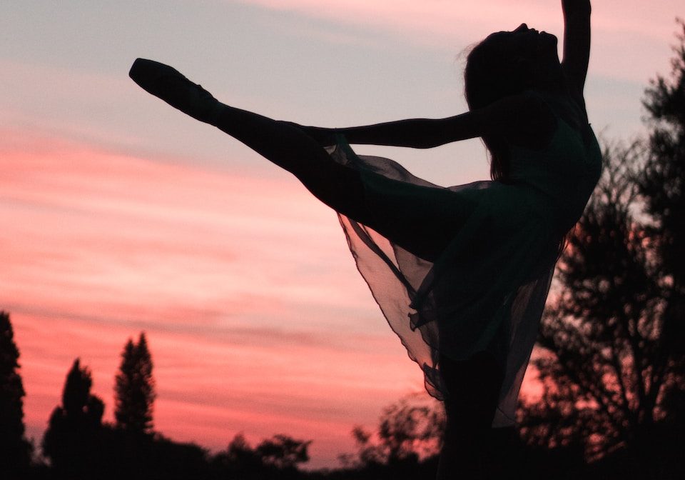 silhouette of woman standing on hammock during sunset