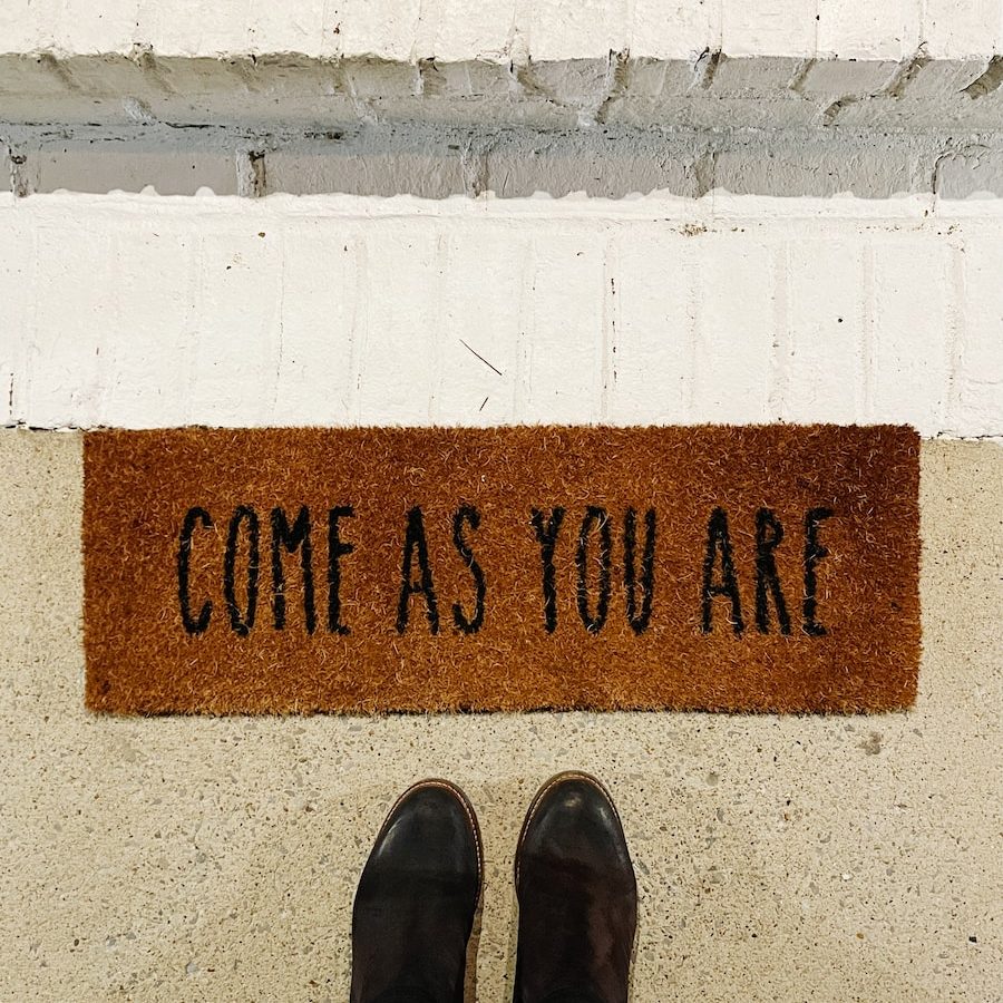 person standing on brown and black welcome printed floor mat